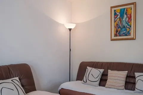Ugao dnevne sobe sa kožnom garniturom, podnom lampom i slikom na zidu. - image 2