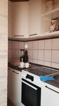 Mala funkcionalna kuhinja sa bijelim elementima i električnim šporetom. - image 7