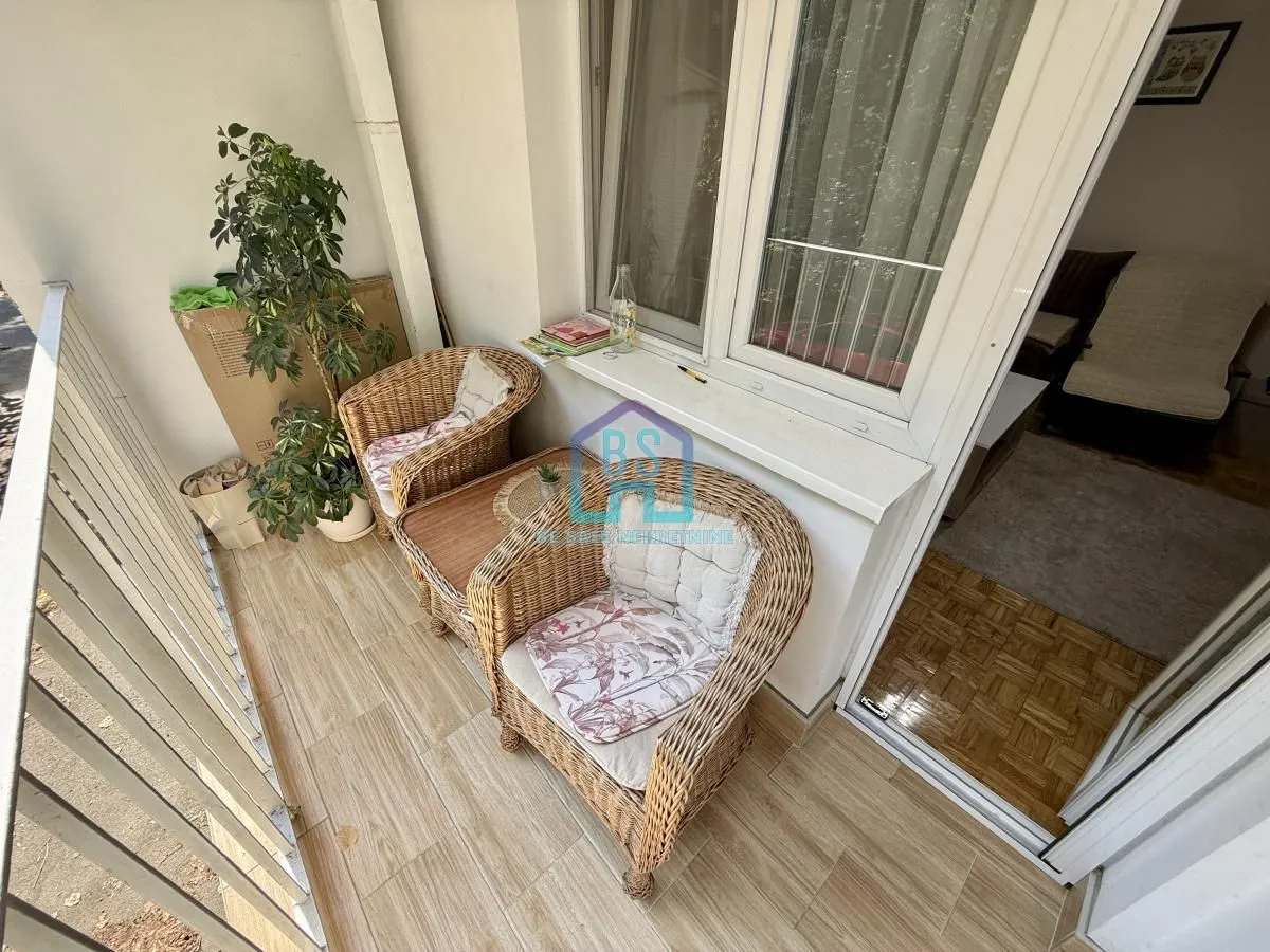 Namešten balkon sa pletenim foteljama i zelenilom.