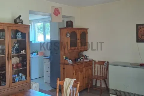 Dnevni boravak sa drvenim nameštajem i pogledom na kuhinju u pozadini. - image 4