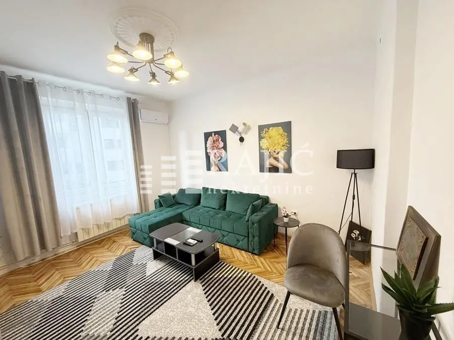 Living room with a green sectional sofa, coffee table, and parquet flooring.