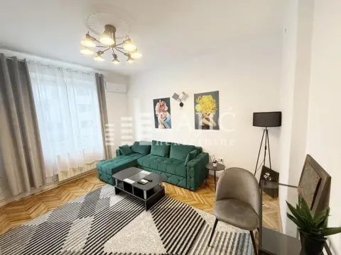 Living room with a green sectional sofa, coffee table, and parquet flooring. - image 3