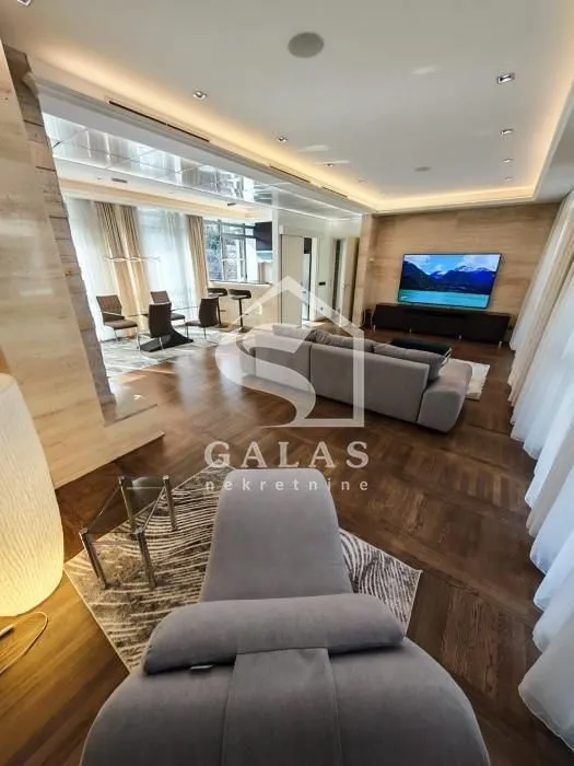 Spacious living room with a sofa, television, and a dining area in the background.