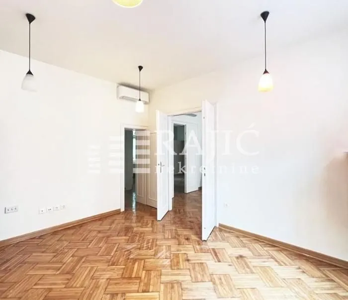 Empty room with parquet flooring and white walls.