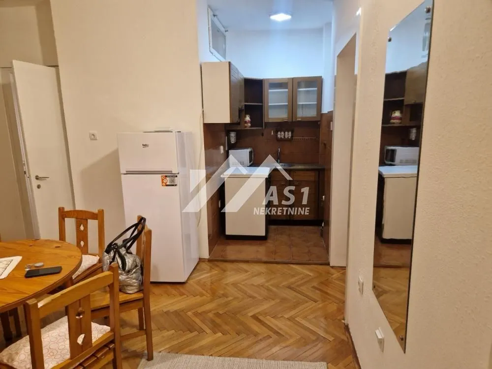 Smaller kitchen with a dining table and wooden parquet flooring.