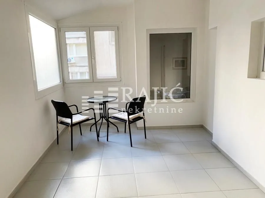 Enclosed terrace with seating set and tiled flooring.