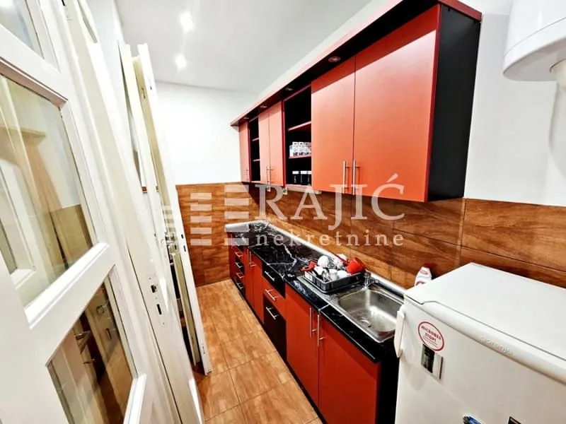 Small kitchen with orange cabinets and a sink.
