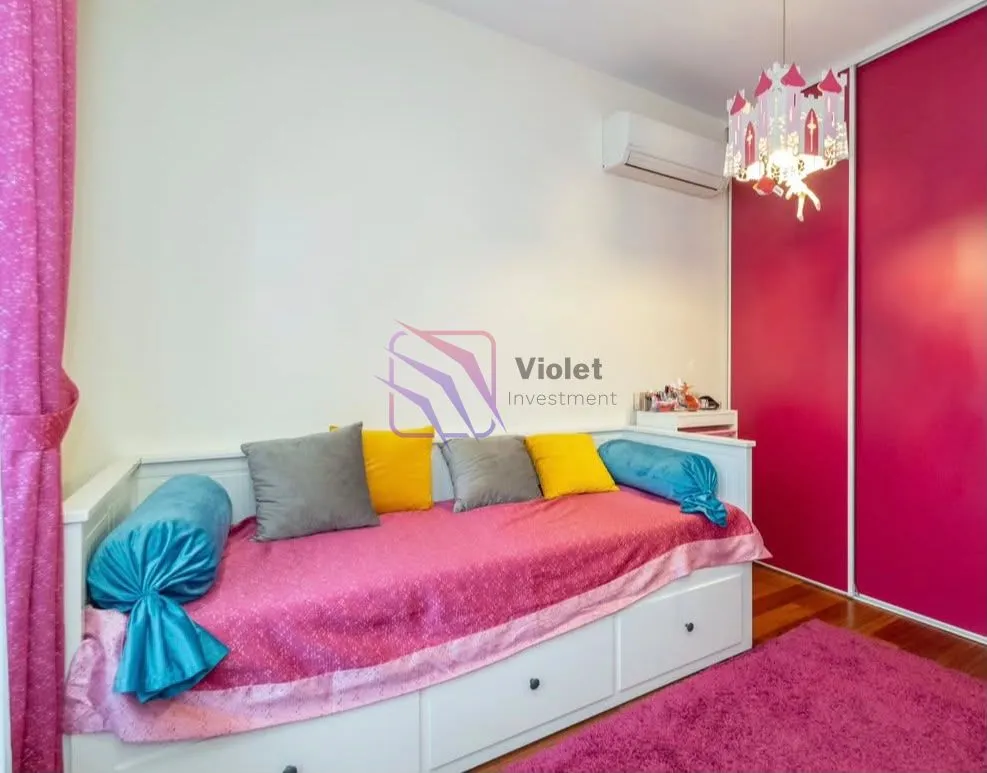 Dječja soba sa krevetom, roze detaljima i ugradnim ormarom.