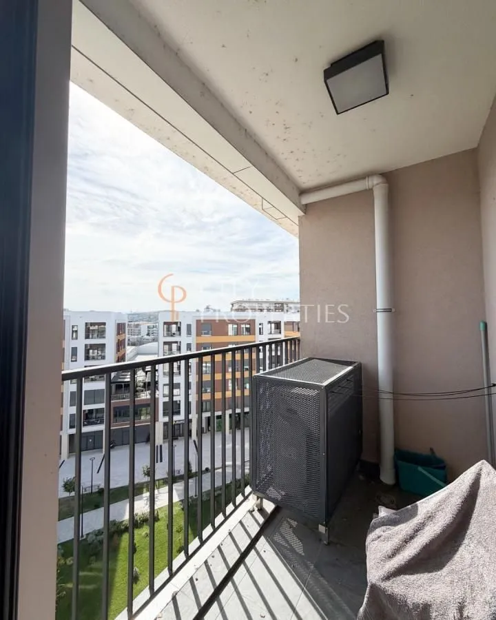 Natkriveni balkon sa pogledom na okolne zgrade i dvorište.