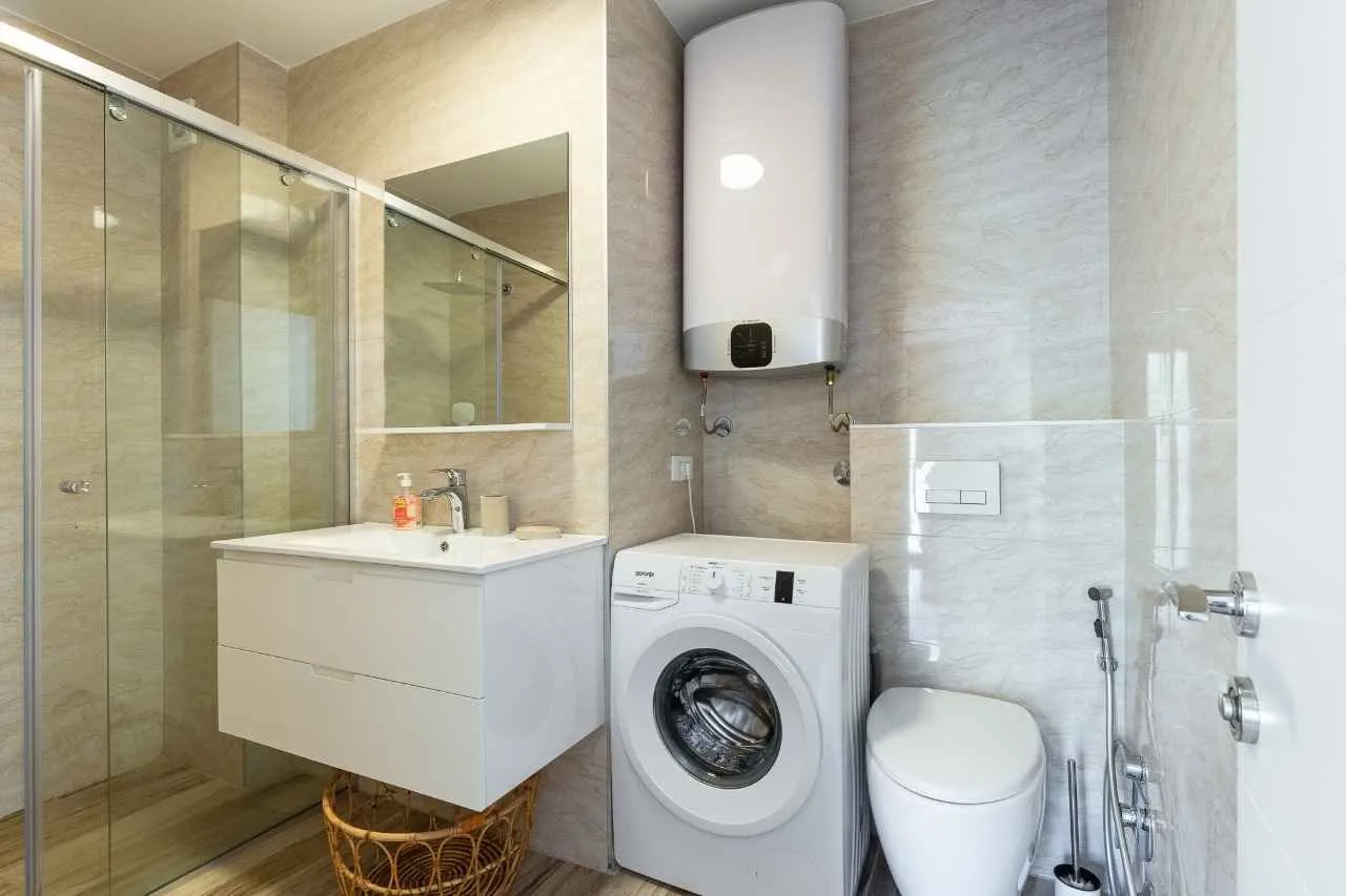 Bathroom with a shower cabin, washbasin, washing machine, and water heater.