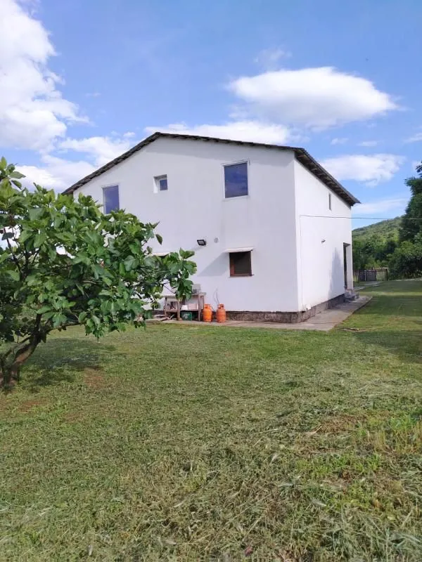 Pogled na dvorište i zadnju stranu kuće sa bijelom fasadom.