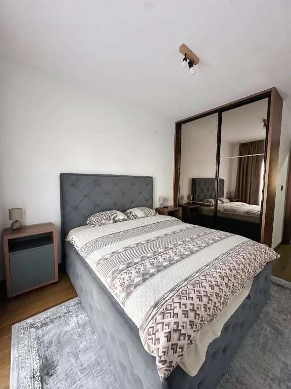 Spavaća soba sa bračnim krevetom, noćnim stočićima i velikim garderoberom sa ogledalom.