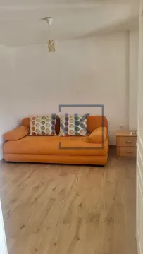 Living room with an orange sofa and a bedside table. - image 3