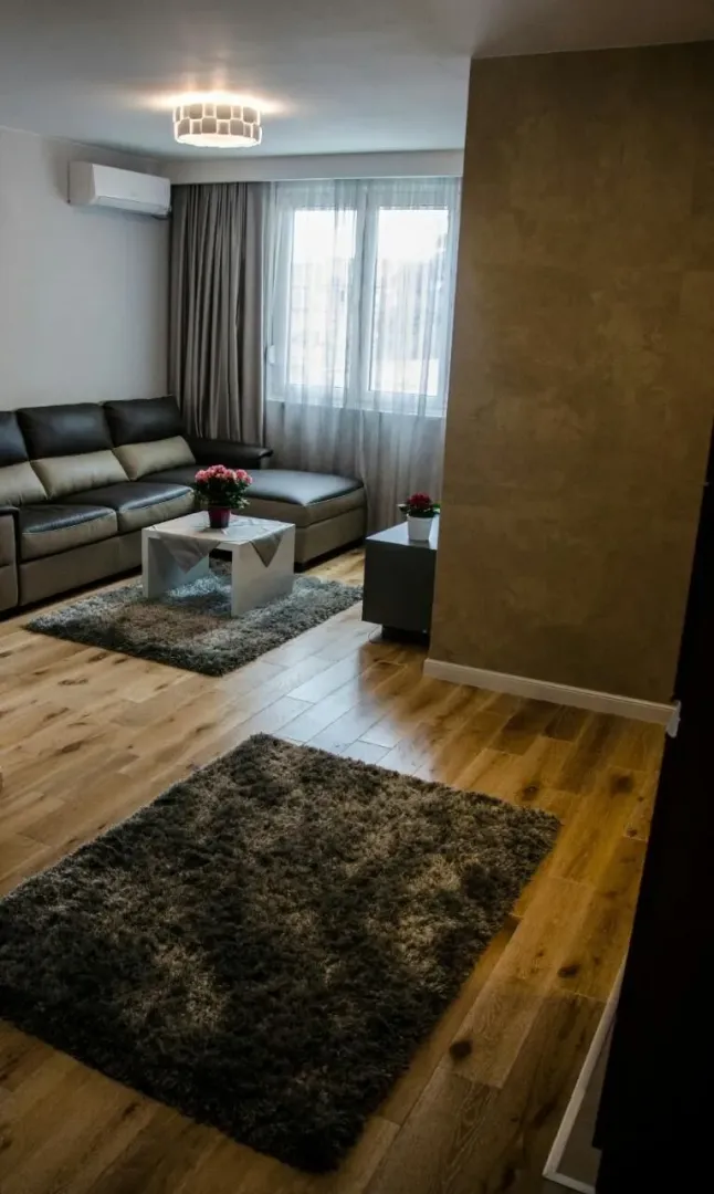 Bright living room with a leather sectional sofa and wooden flooring.