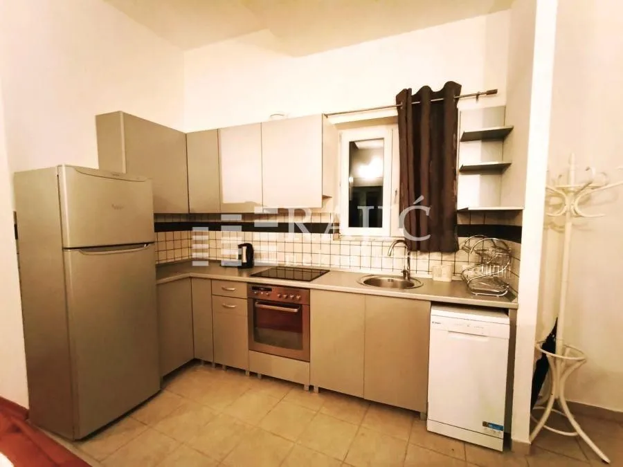 Small equipped kitchen with white goods and cabinets.