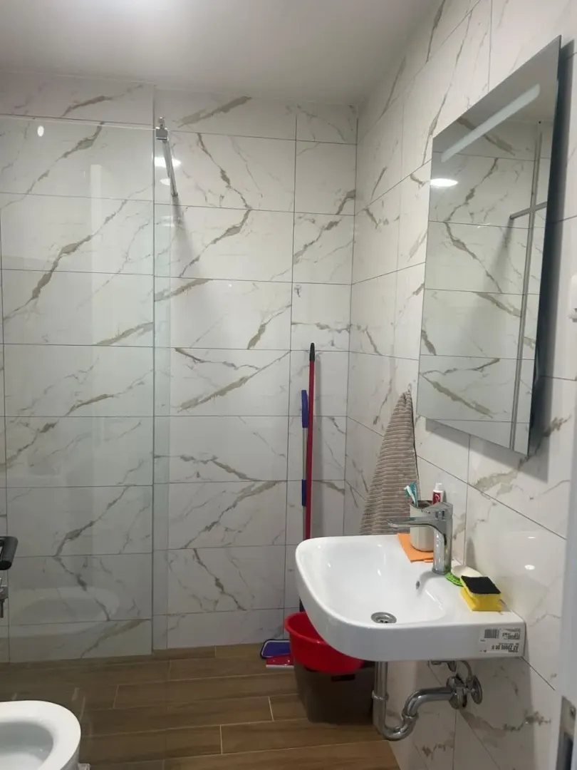 Small bathroom with a sink, mirror, and shower enclosure.