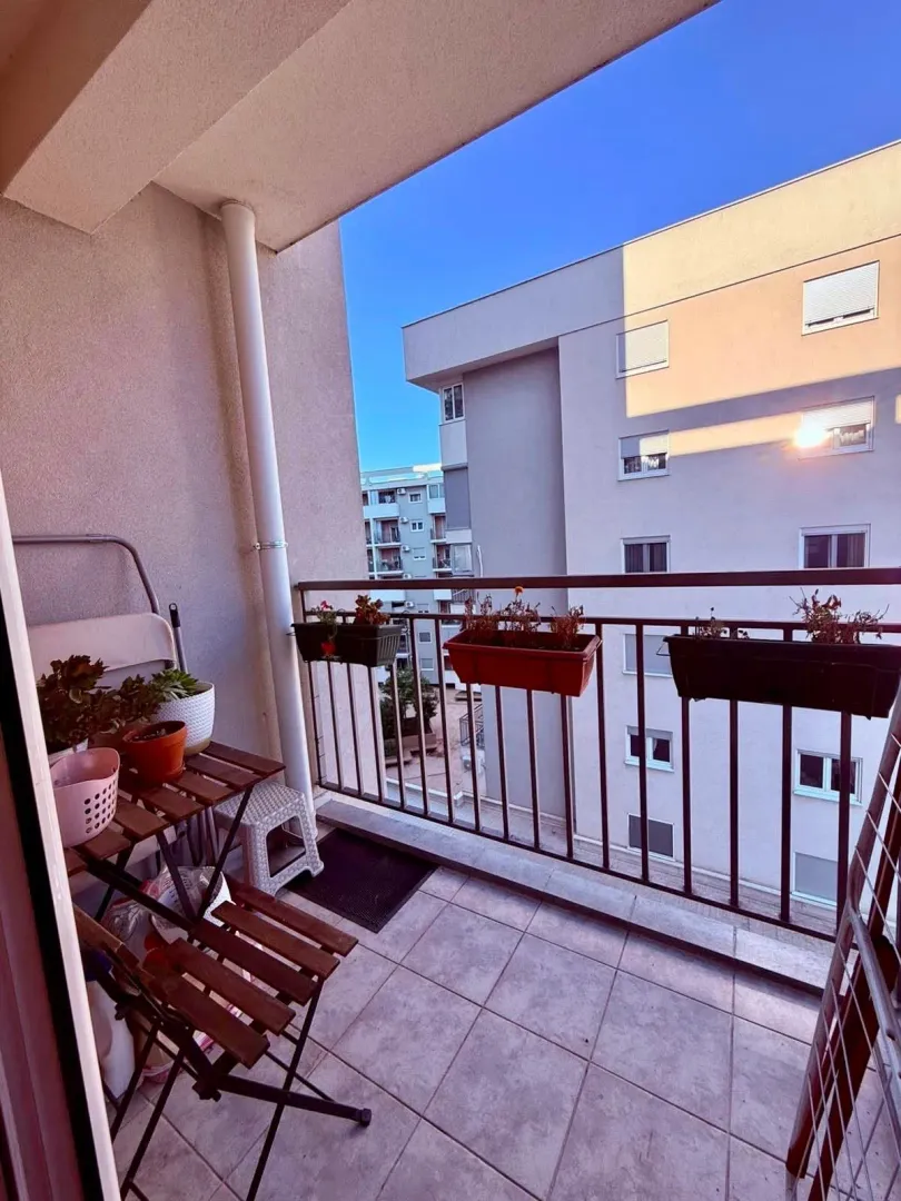Smaller furnished balcony with a table, chairs, and potted flowers.