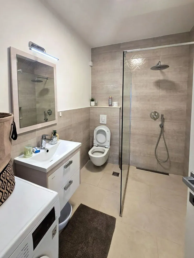 Moderno opremljeno kupatilo sa tuš kabinom, umivaonikom i WC šoljom.