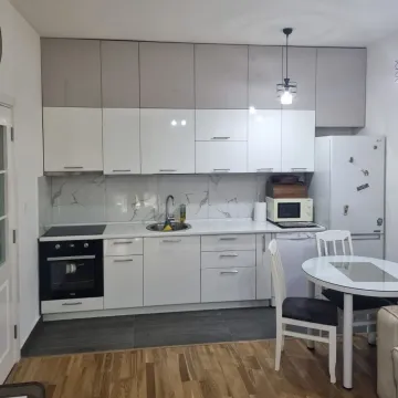 Moderna kuhinja sa bijelim elementima i trpezarijskim stolom. - image 3