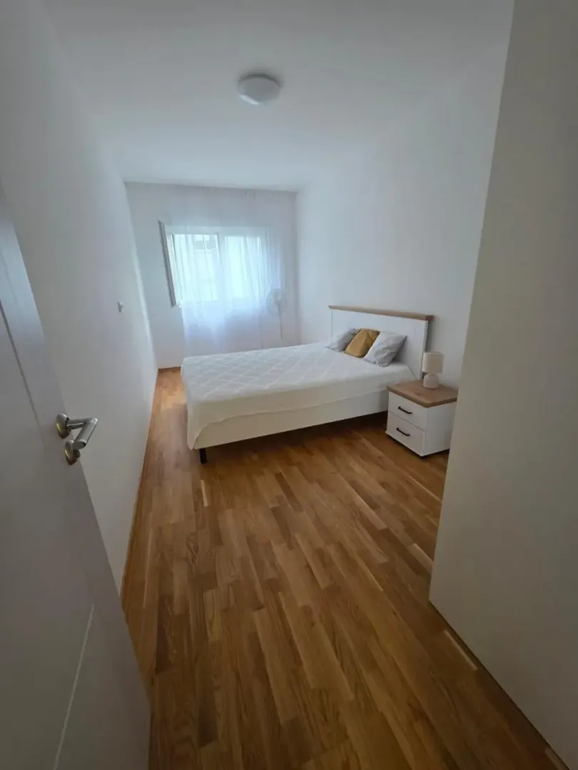 Namještena spavaća soba sa bračnim krevetom i drvenim podom.