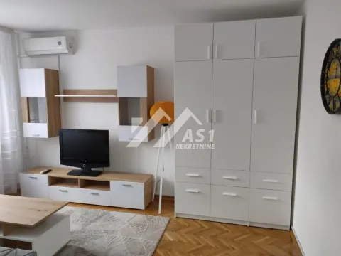 Dnevna soba sa televizorom, nameštajem i velikim belim ormarom. - image 4