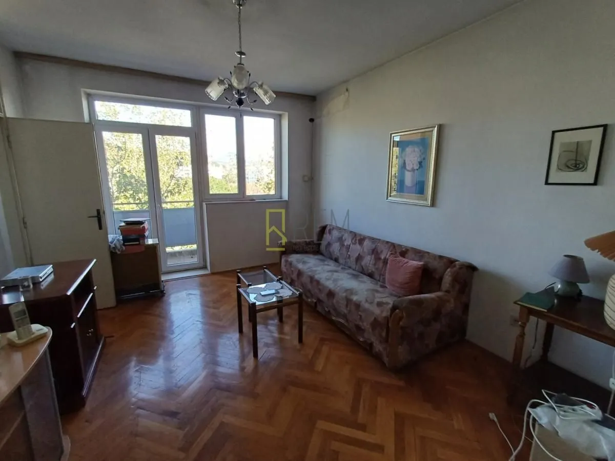 Dnevna soba sa garniturom, parketom i izlazom na terasu.