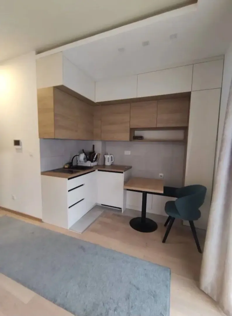 Small modern kitchen with white and wooden elements and a dining table.