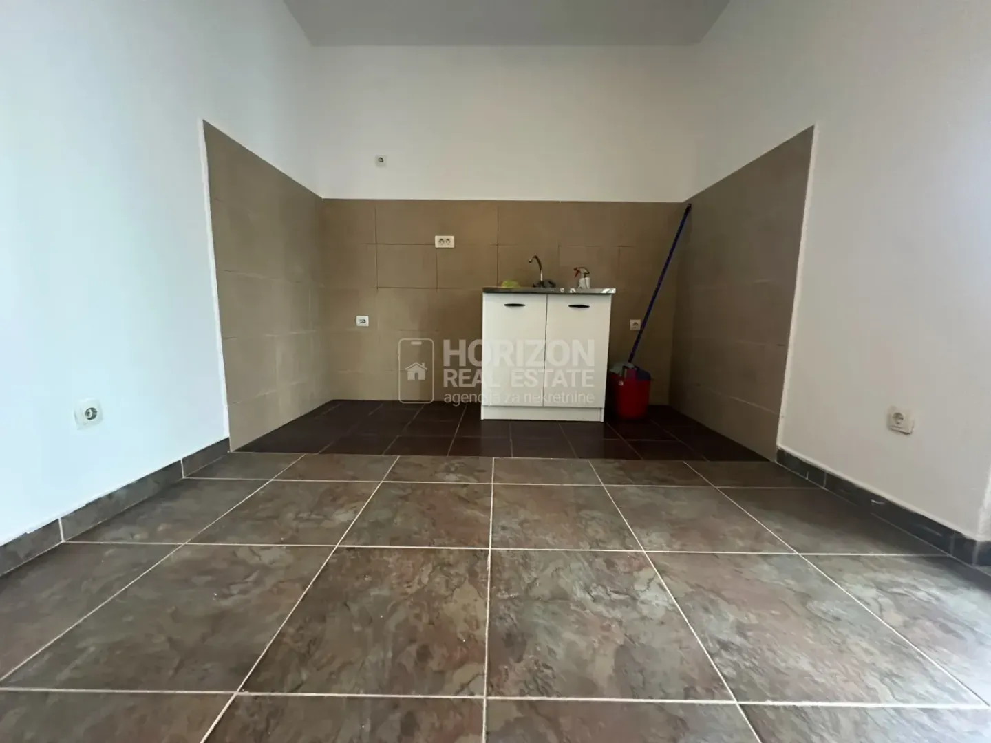 Empty kitchen with a sink and ceramic tiles.