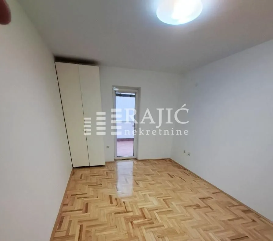 Empty room with parquet flooring and a wardrobe.