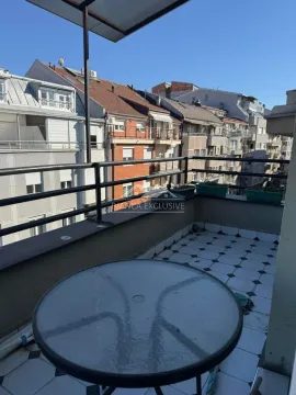 Natkrivena terasa sa stolom i pogledom na okolne zgrade. - image 11