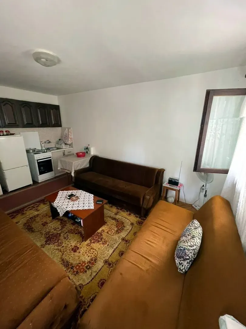 Living room with a seating area and a small kitchenette in the corner.