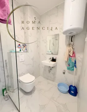 Small bathroom with white marble tiles, a walk-in shower, and sanitary fixtures. - image 9