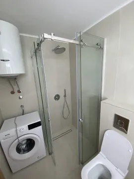 Svijetlo kupatilo sa staklenom tuš kabinom i veš mašinom. - image 7