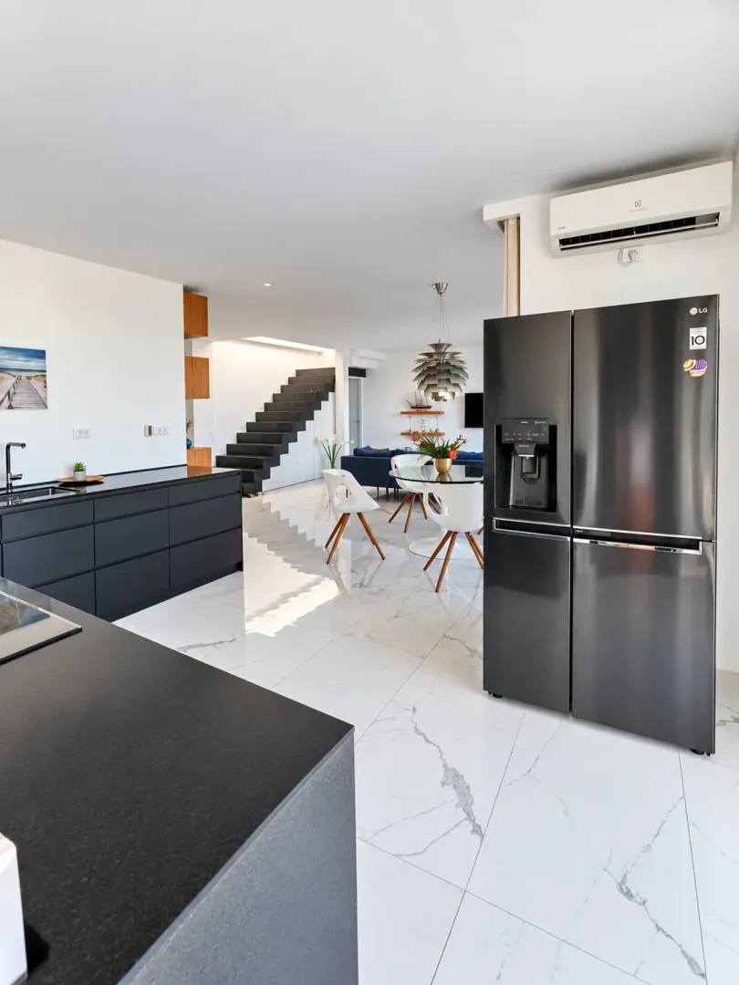 Modern kitchen with black cabinetry and an adjoining dining area.