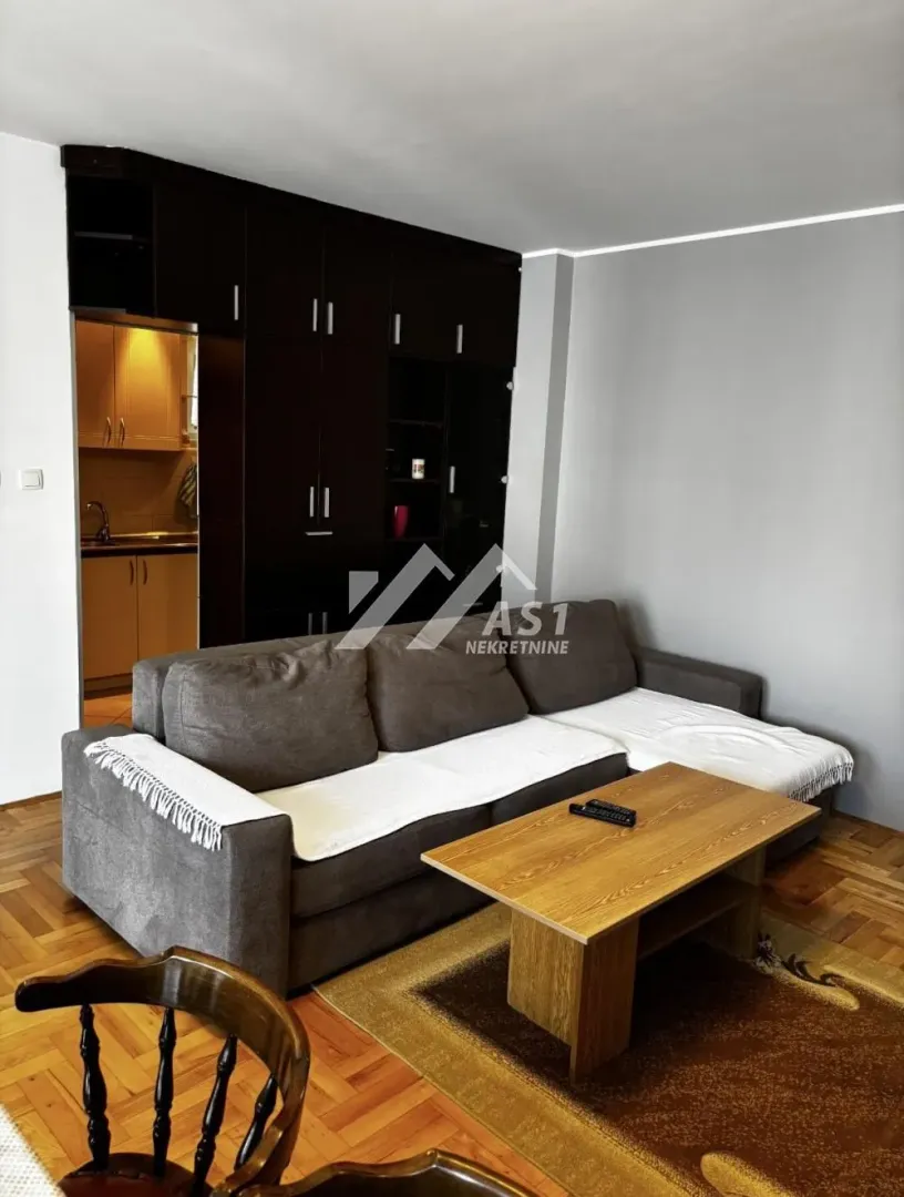 Living room with a sofa, coffee table, and a view of the kitchen.