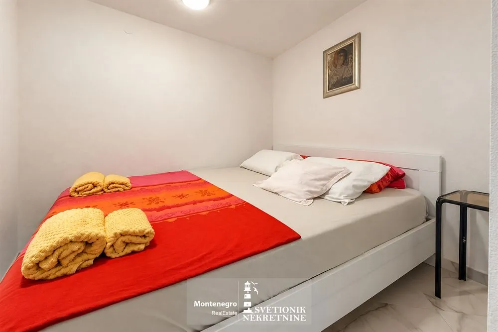 Manja spavaća soba sa bračnim krevetom i uramljenom slikom na zidu.
