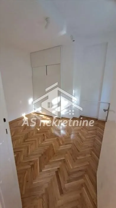 Empty bedroom with parquet flooring and a built-in wardrobe.