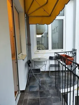 Small furnished balcony with a table, chairs, and a protective awning. - image 10