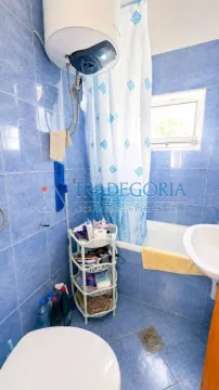 Tiled bathroom with a bathtub, washbasin, toilet, and water heater. - image 9