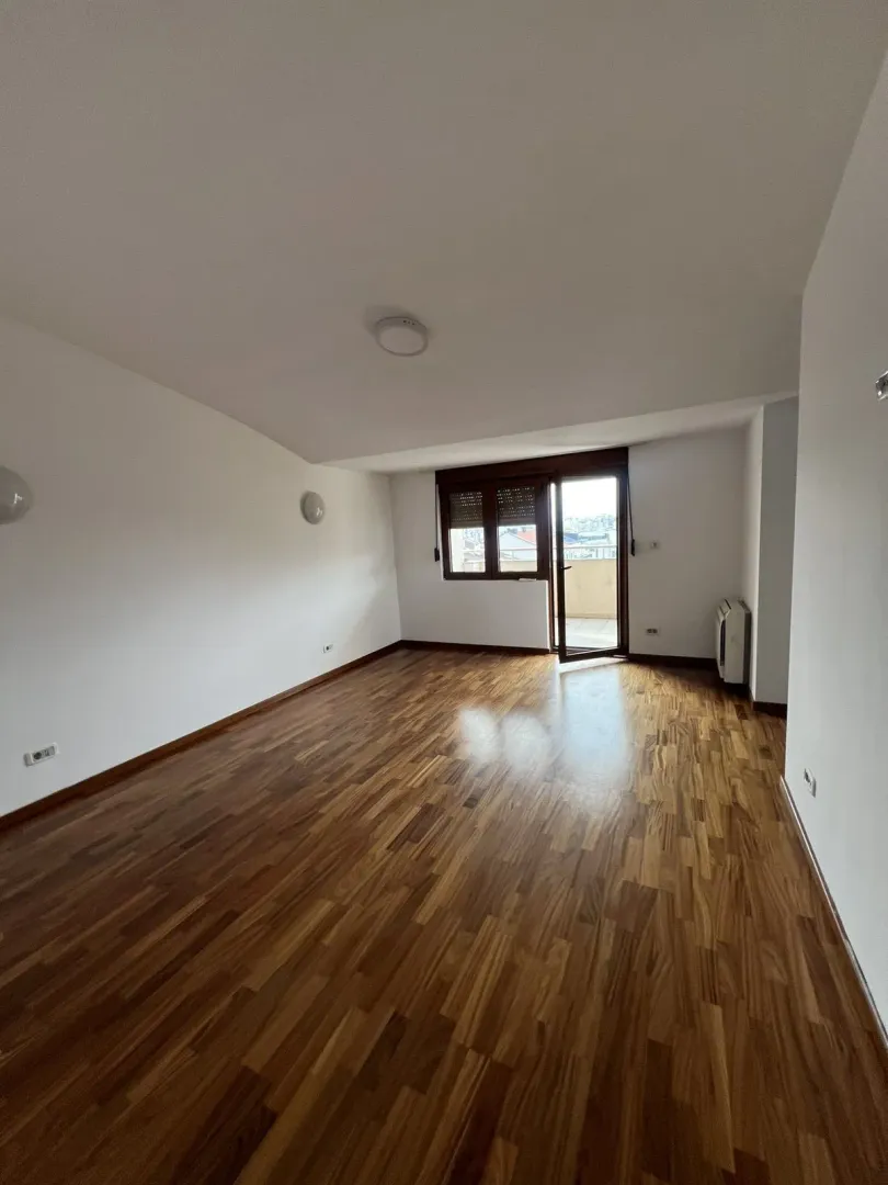 An empty room with parquet flooring and balcony access.
