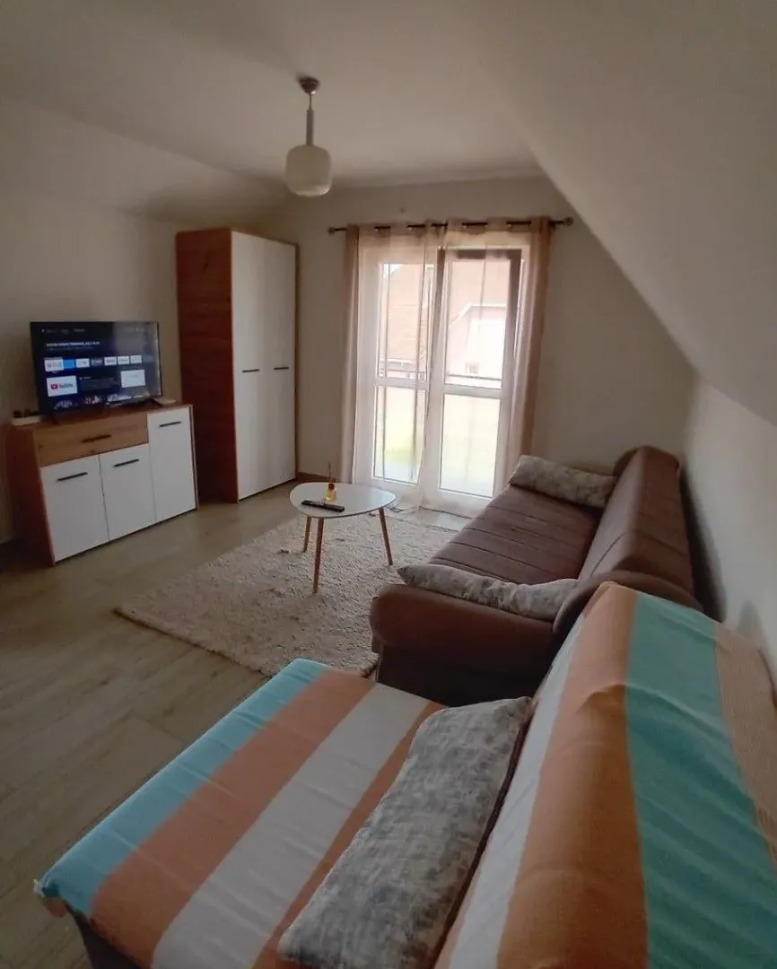 Dnevna soba sa garniturom, televizorom i izlazom na terasu.
