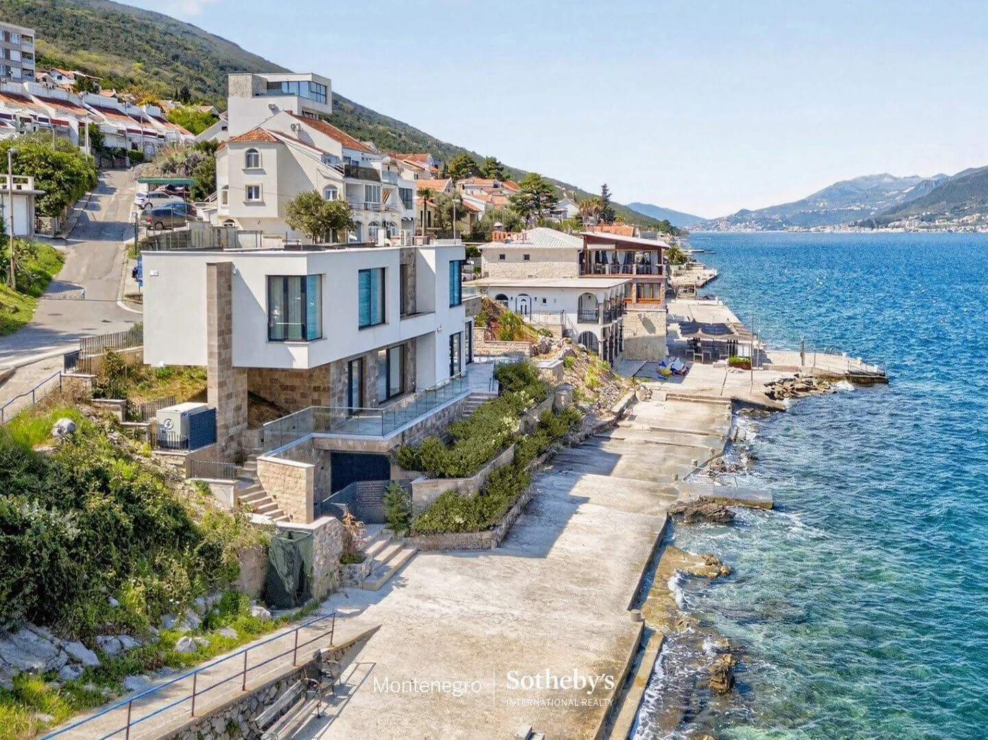 Pogled iz vazduha na modernu vilu pored mora i okolnu obalu.