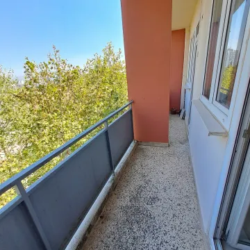 Dugačka terasa sa metalnom ogradom i pogledom na zeleno drveće. - image 16