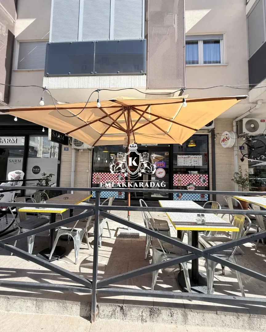 Eksterijer poslovnog prostora sa baštom i suncobranom.