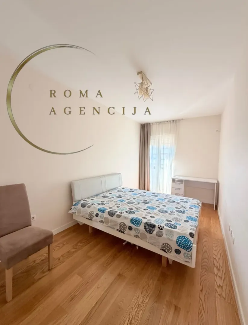 Bright bedroom with a double bed, wooden flooring, and a desk.