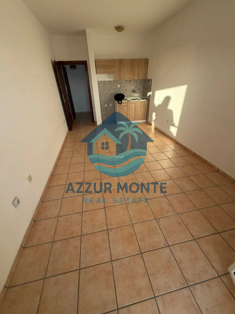 Empty kitchen with wooden cabinets and ceramic floor tiles.