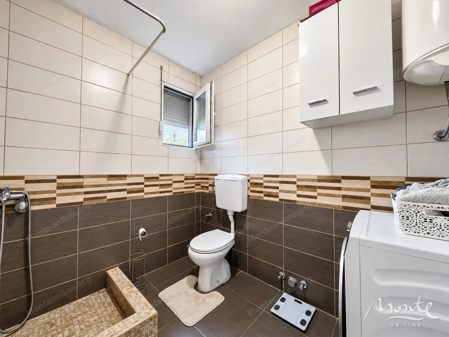 Kompaktno kupatilo sa WC šoljom, tuš kabinom, ormarićem i mašinom za veš.