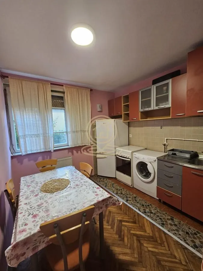 Kuhinja sa trpezarijom i elementima u boji drveta.
