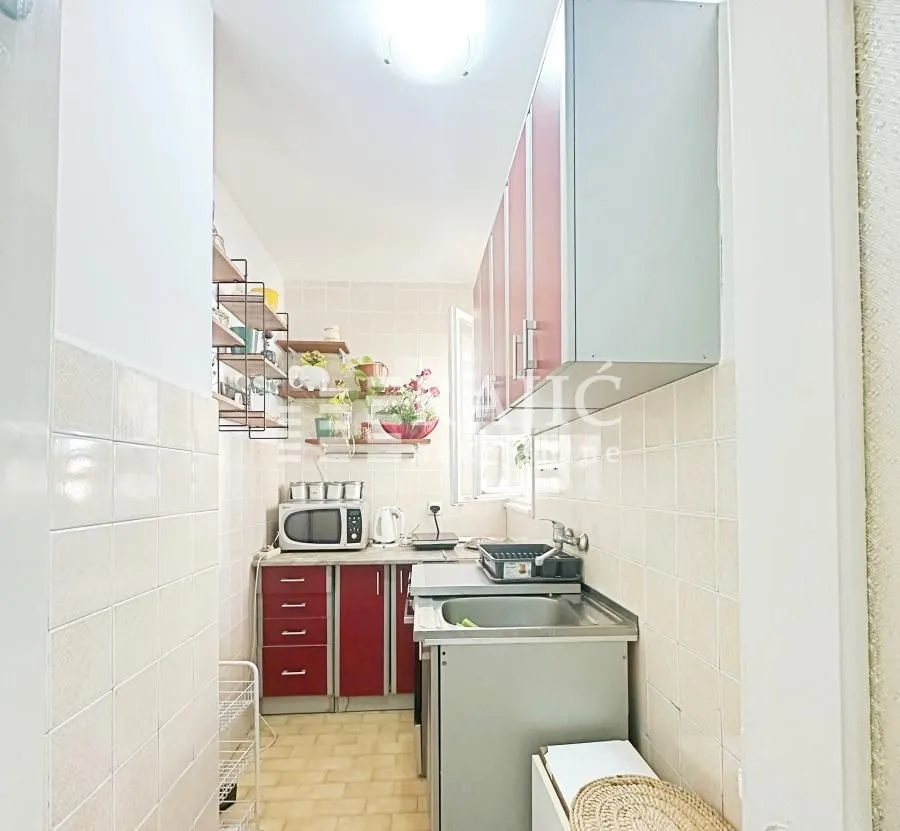 Smaller kitchen with red cabinets and white tiles.