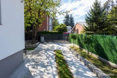 Popločano dvorište sa stazom, zelenilom i ogradom ispred kuća. - image 2